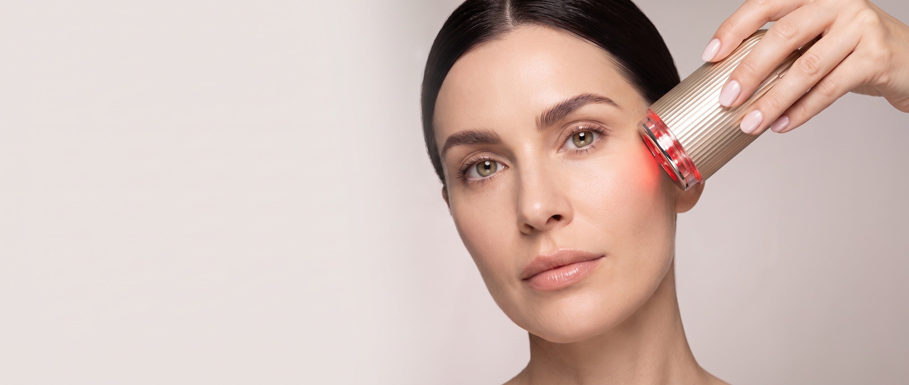 Woman using the champagne-gold FLOW+ device on her cheek